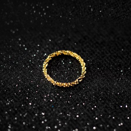 A close-up of a gold bling ring from the set on a black glitter background.