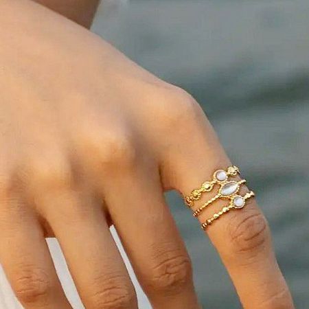A model wearing a stack of three gold rings from the set, showing their versatility.