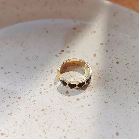 Detailed view of a gold-plated ring with black enamel heart inlays.