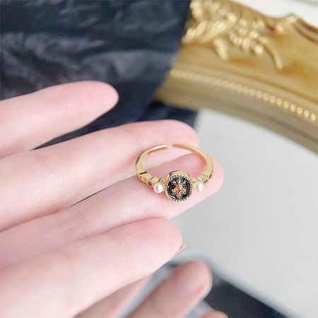 Retro gold plated open ring with a black and orange gemstone and pearl details.