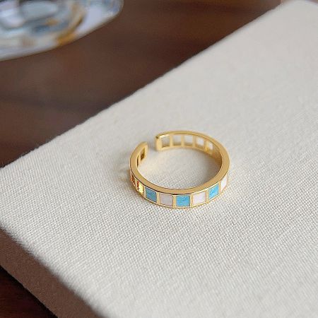 Another ring from the set with intricate blue and white inlays on a gold-plated band.