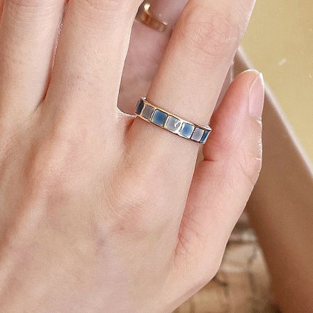 The gold-plated enamel ring worn on a finger to show scale and style.