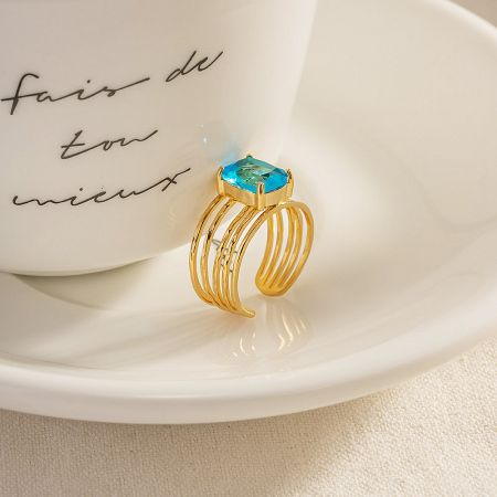 The gold and blue zirconia ring elegantly styled on a white saucer next to a teacup.