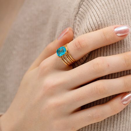 Stylish product image showcasing the gold open finger ring with its vibrant blue stone.