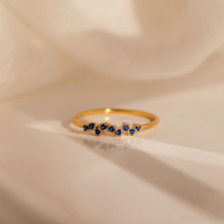 Close-up of a single gold-plated birthstone ring with vibrant blue marquise and round CZ stones.