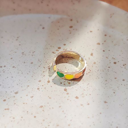 A gold-plated open ring with vibrant, multi-colored enamel accents.