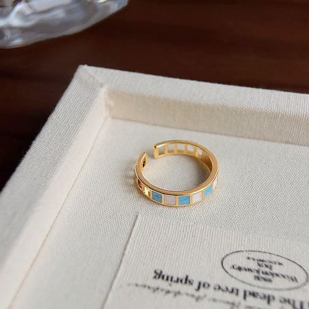 A detailed view of a gold ring from the set, highlighting the colorful geometric enamel patterns.