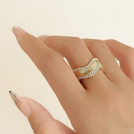 Detailed view of a gold ring with a wavy design and diamond-like zircon accents.