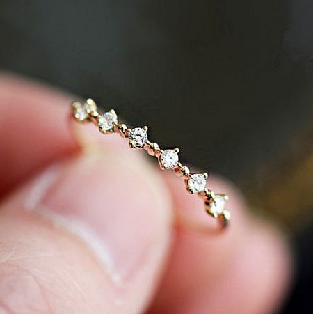 Close-up of a gold-plated 925 sterling silver ring with a wavy band and sparkling zircon stones.