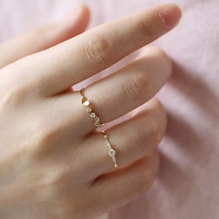 Detailed view of a gold-plated sterling silver ring with a unique staggered design of heart and round zircon stones.