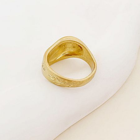 Showcase of the detailed engraving on a gold brass band ring.