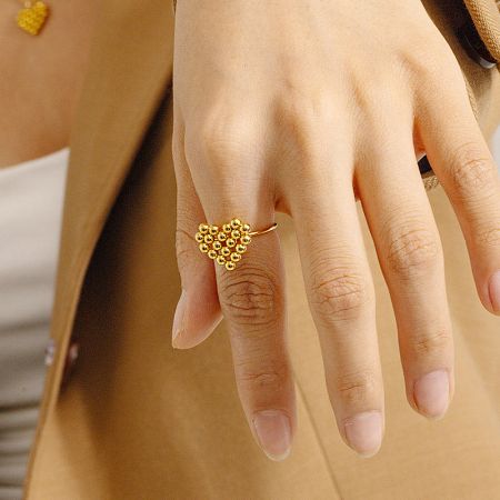A gold-tone adjustable ring with an intricate flower-like bead design.