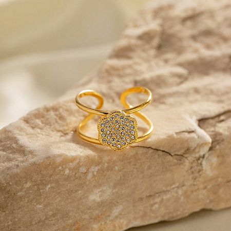 Detailed shot of a gold ring with an intricate flower-shaped cubic zirconia centerpiece.