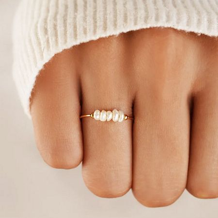 Close-up of a single 18K gold-plated stainless steel ring with four delicate baroque freshwater pearls worn on a finger.