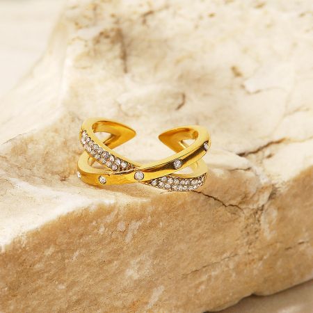 Detailed view of a gold-plated zircon crisscross ring on a stone surface.