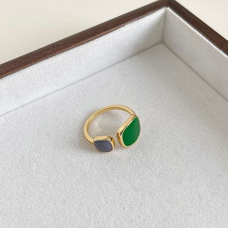 A retro gold-plated ring with gray and green stones displayed in a white jewelry box.