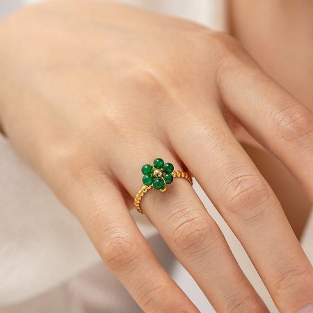 Close-up of a gold ring with a delicate green gemstone flower.