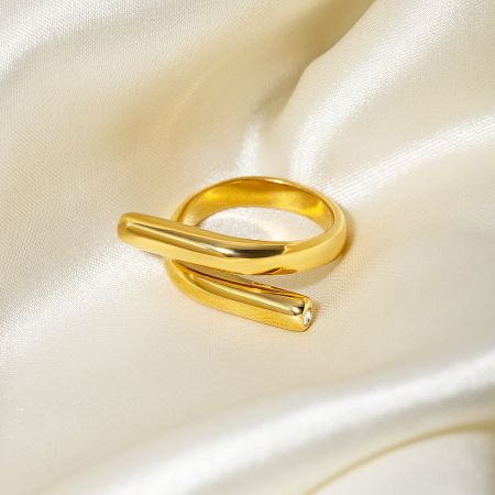 Detailed view of a single gold ring with an intersecting bar design from the set.