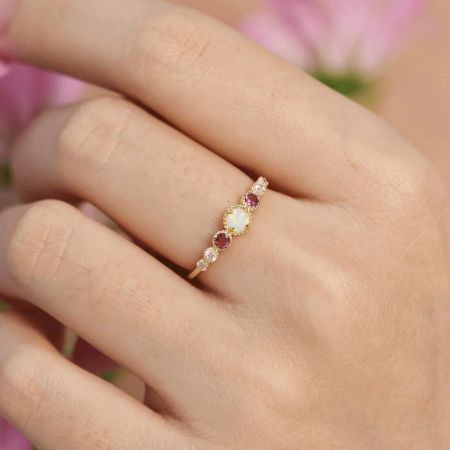 Close-up view of the opal and zircon ring worn on a finger, showcasing its brilliant sparkle.