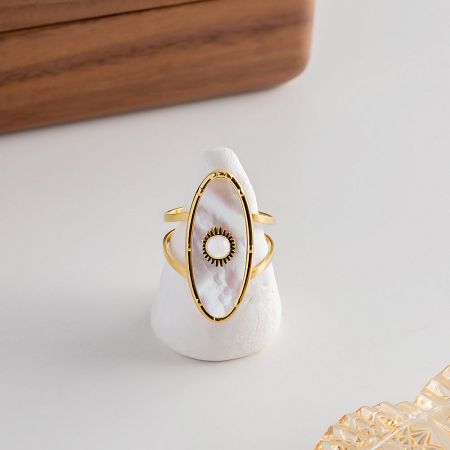 A unique gold ring from the set featuring an oval white shell inlay with a sunburst design.