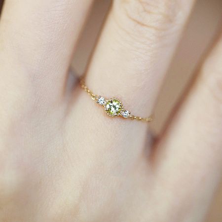 A gold-finished adjustable ring from the set, worn on a finger, showcasing a pale yellow gemstone.
