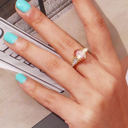 Wholesale Stainless Steel Oval Zirconia Adjustable Gemstone Rings (Set of 5) - A close-up of the stainless steel oval zirconia adjustable gemstone ring in a champagne gold finish, showcasing the large central stone and side accents.