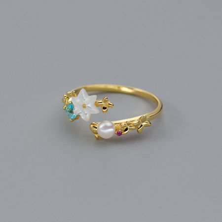 Detailed view of a sterling silver gold-plated ring with pearl and flower stone.