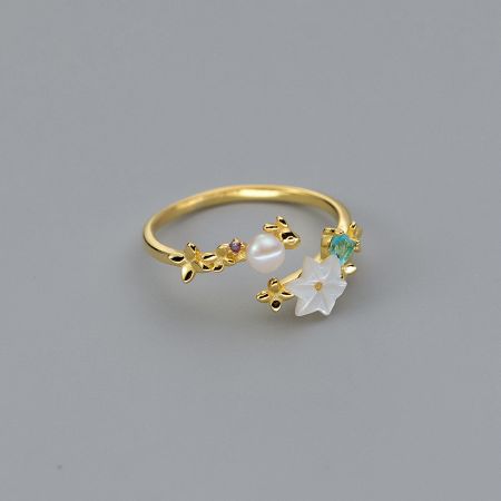 A unique gold ring from the set with pearl, star, and floral motifs.