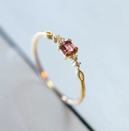 Angled view of the gold-plated sterling silver ring, displaying the elegant setting of the pinkish-red gemstone.