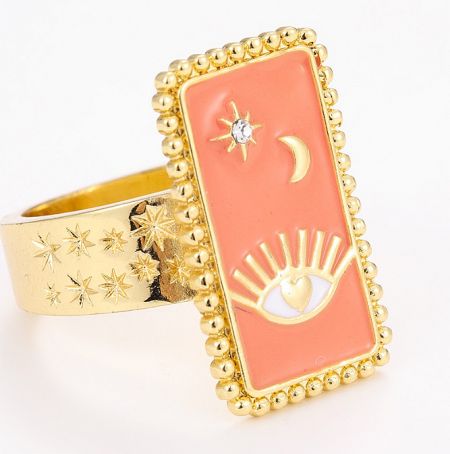 Close-up of a gold Tarot Card Enamel Ring featuring a pink stone and detailed celestial engravings.