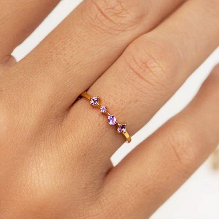 The sterling silver stacking ring with vibrant purple zircons displayed on a hand.