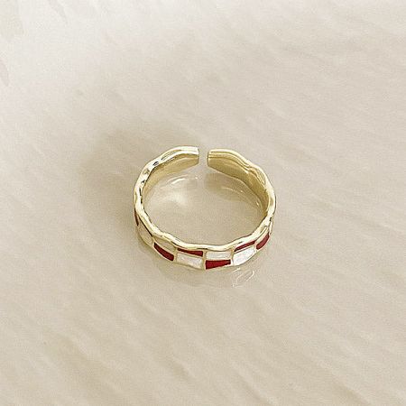 Detailed view of a single adjustable open ring with intricate red and white enamel inlays.