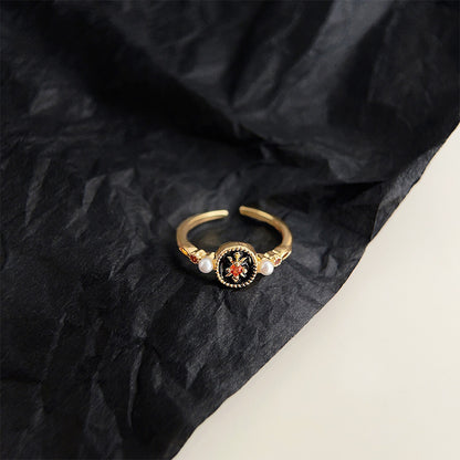 Close-up of a gold plated ring featuring a vibrant red gemstone and classic pearls.