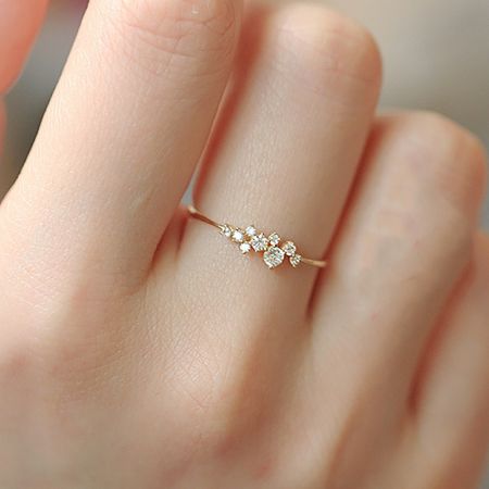 Close-up of a minimalist gold-plated ring featuring small, brilliant cubic zirconia stones.