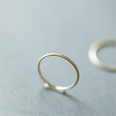 925 Sterling Silver Minimalist Stackable Thin Ring Band Set of 5 - A minimalist 925 sterling silver stackable ring with a textured gold finish, shown on its side to detail the craftsmanship.