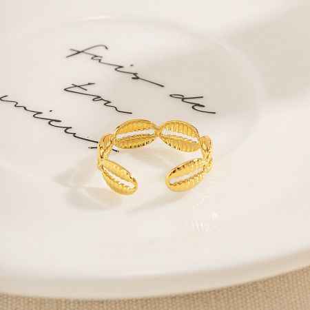 A unique textured oval design gold ring from the set of five, on a decorative plate.