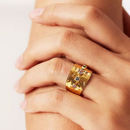 Detailed view of the adjustable cuff ring with three small gemstones on a hand.