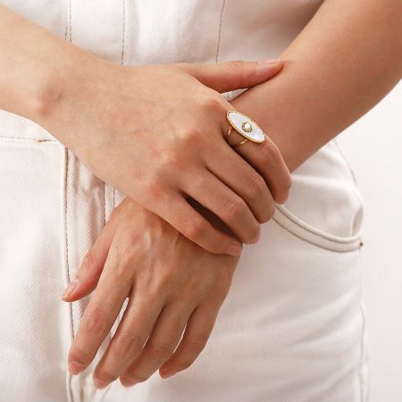 Lifestyle image of the sunburst gold ring with a white stone worn on a hand.