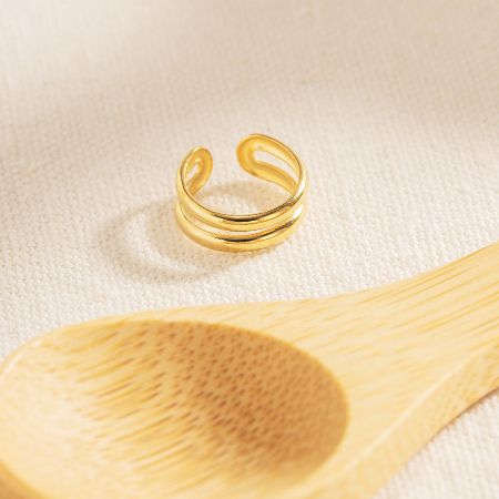 Gold ear cuff displayed on a wooden spoon for a lifestyle shot.