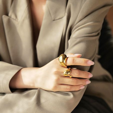 A hand model showcasing the bold design of the gold chunky rings.