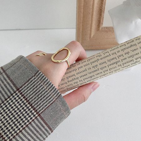 Lifestyle view of the 18K gold plated oval open rings worn on a model's hand.