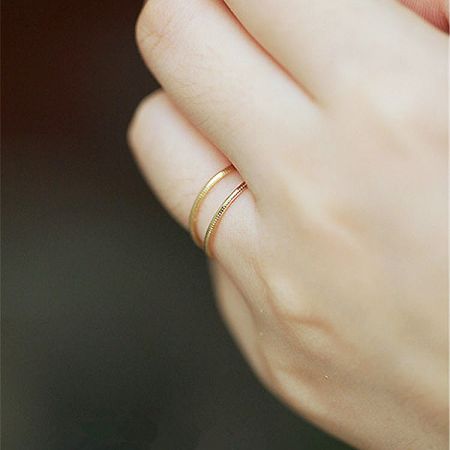 Two thin gold stackable rings worn on a finger for a minimalist look.