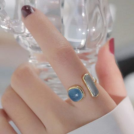 Close-up of two adjustable rings with blue and gray enamel stones on a finger.