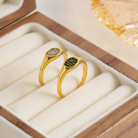 The green and white zircon signet rings elegantly displayed in a wooden jewelry box.
