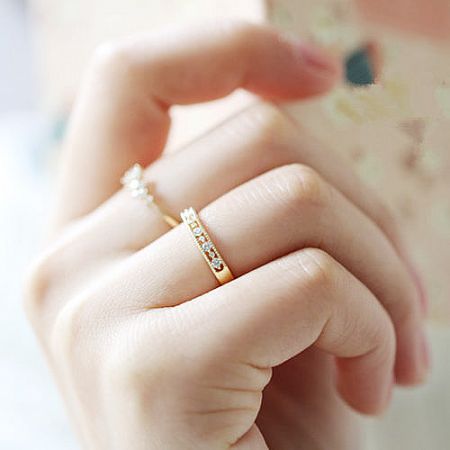 A model's hand wearing two rings from the minimalist engagement set.