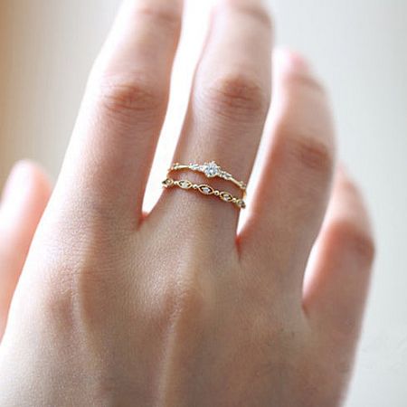 A model's hand wearing multiple gold zircon rings from the sterling silver set, demonstrating a stylish layered look.