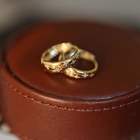 Detailed shot of the gold star hoop earrings on a leather case, highlighting the craftsmanship.