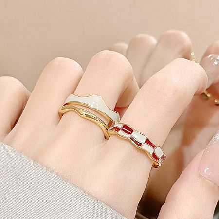 Close-up of two gold-plated rings with red and white enamel checkerboard patterns.