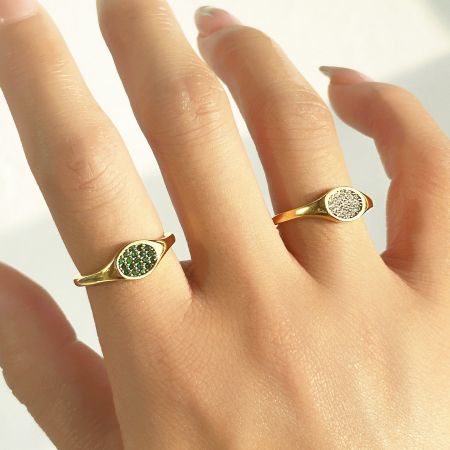 Model's hand wearing two stainless steel micro pave zircon rings, one with green stones and one with white stones.