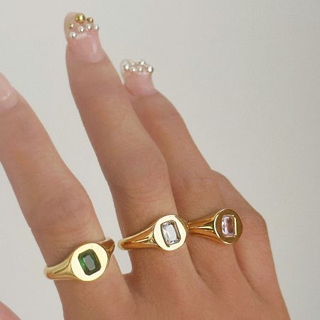 Top-down view of the stainless steel signet rings with green and white CZ stones.